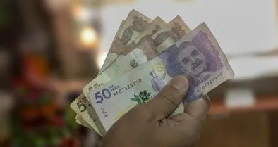 Money from Colombia, Man holding peso bills in front of him, Business investments, Creative financial concept