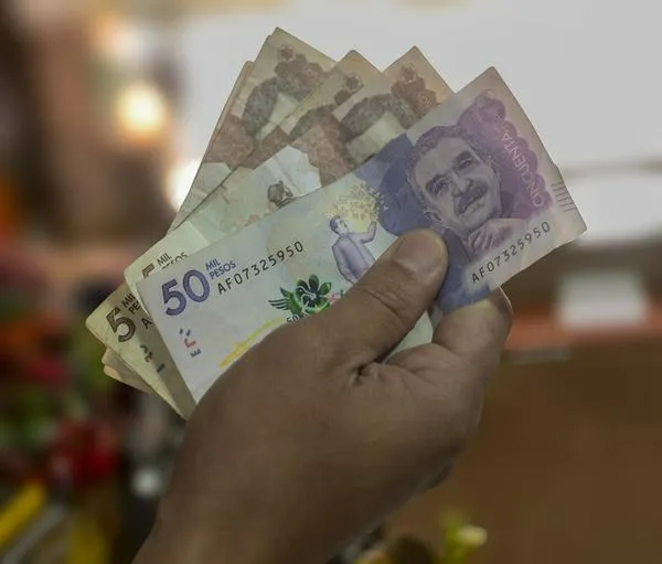 Money from Colombia, Man holding peso bills in front of him, Business investments, Creative financial concept