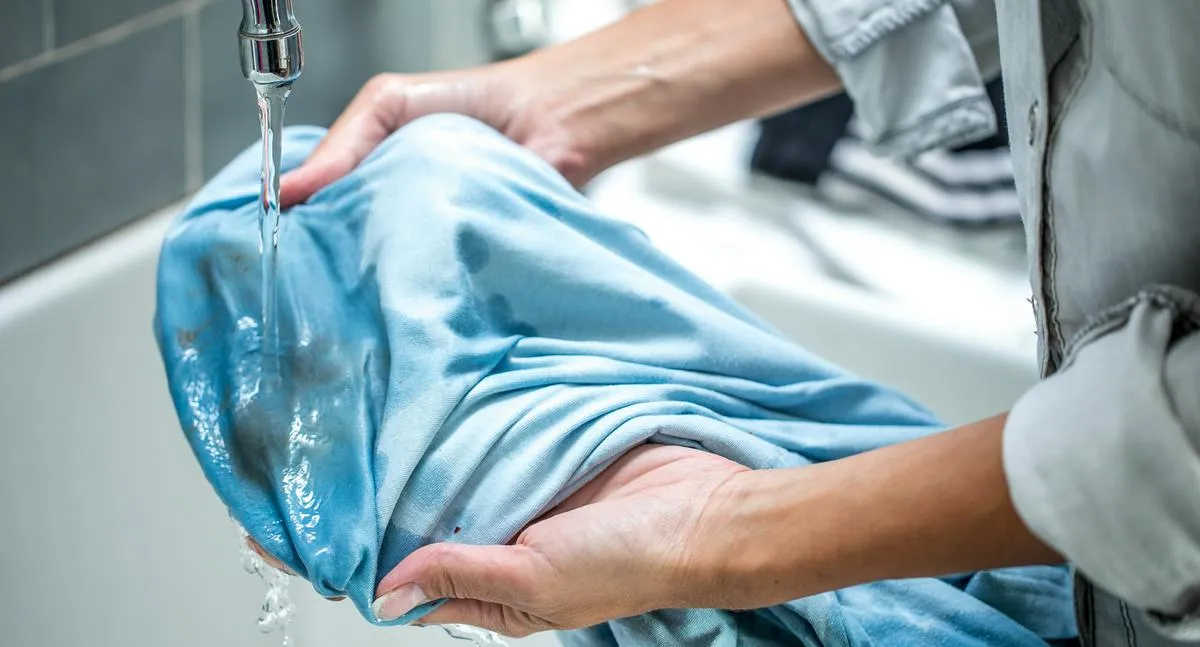 Woman Cleaning Stained Shirt in Bathroom Sink.