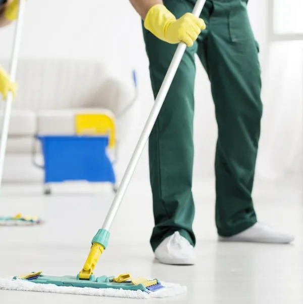 Cleaning team wiping the floor using mops in the flat