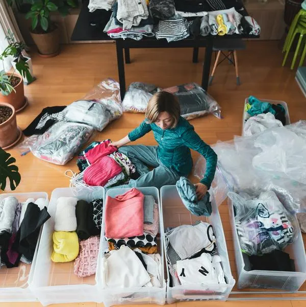 a woman organizes clothes in living room of her home.