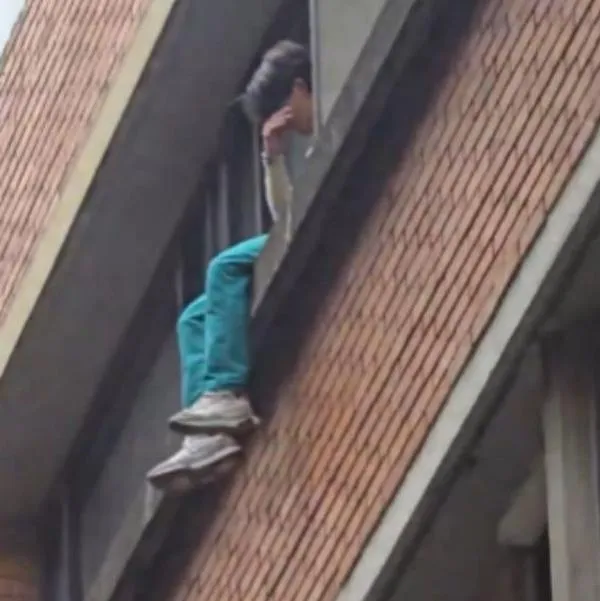 Momento en el que un joven se sienta sobre una ventana de los juzgados de Paloquemao, en Bogotá