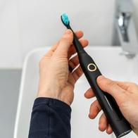 Pov woman hold professional sonic electric toothbrush with replaceable brush in hands over sink on blurred background. Wireless equipment and oral care concept