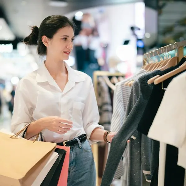 Smiling young woman holding shopping bags in a clothing store at a modern shopping mall
