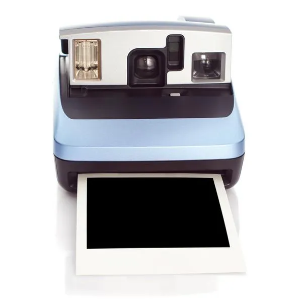 Metalic blue colored Instant film camera with a blank instant print photo from 90's on white background