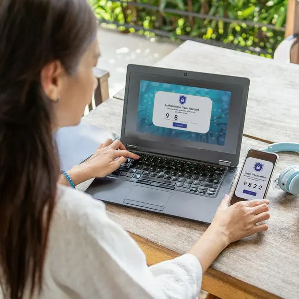 Mujer comprobando la protección de sus cuentas digitales en el portátil y el móvil.