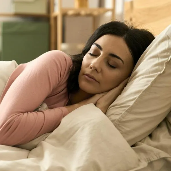 Woman rests peacefully in bed, eyes closed, enjoying comfortable sleep in bedroom