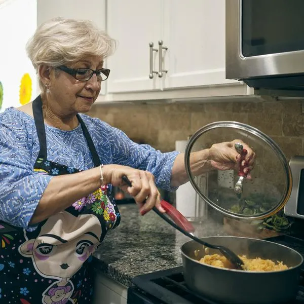 A hispanic grandmother preparing food in a home kitchen for a family party.