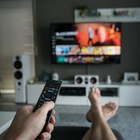 A young man is browsing through television channels with a remote control.