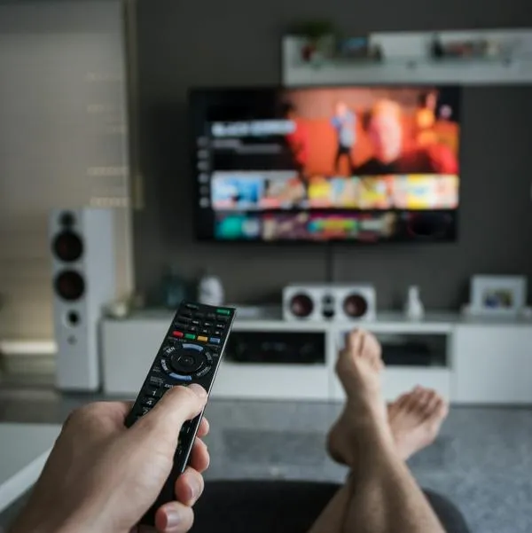 A young man is browsing through television channels with a remote control.