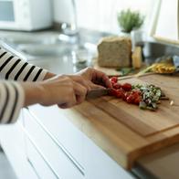 Close-up of woman cooking in kitchen at home cutting vegetables