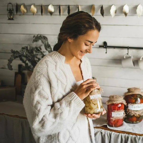 Homemade fermented vegetables canned in jars. Making fermented pickled tomatoes. Canning process, fresh vegetables, jars with preserved vegetarian food on wood rustic table. Healthy eco food and zero waste food concept. Kitchen pantry.