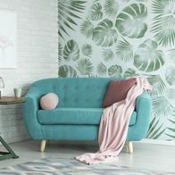 Green table with plant between pink chair and blue sofa in floral living room with wallpaper and poster