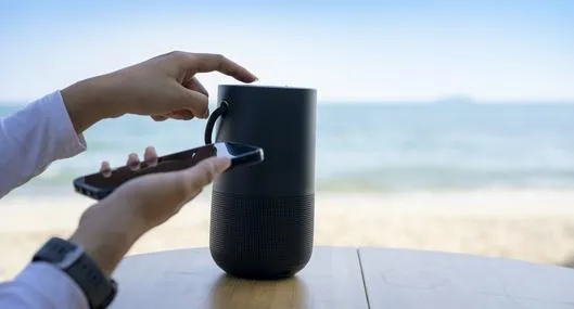 Hands connecting cell phone with bluetooth speaker with beach background, Vacation activity.